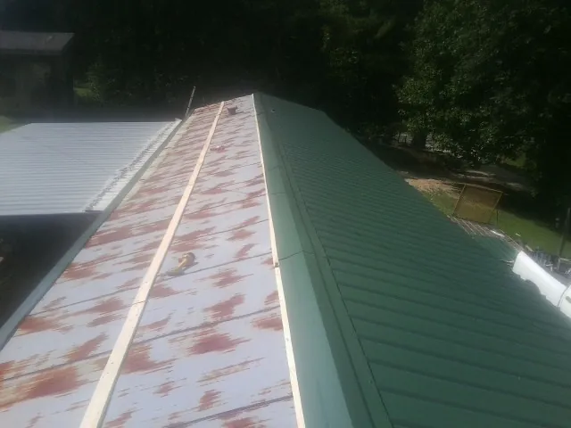 Old rusted panels beside newly installed green metal roofing — Wind Damage Roof Repair by Roofing Brothers in La Quinta