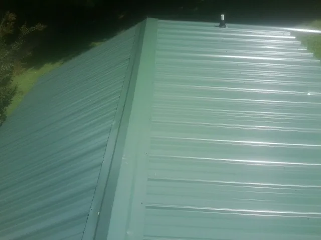 New green metal panels meeting at the ridge of a roof — Flat Roof Repair work by our crew in La Quinta