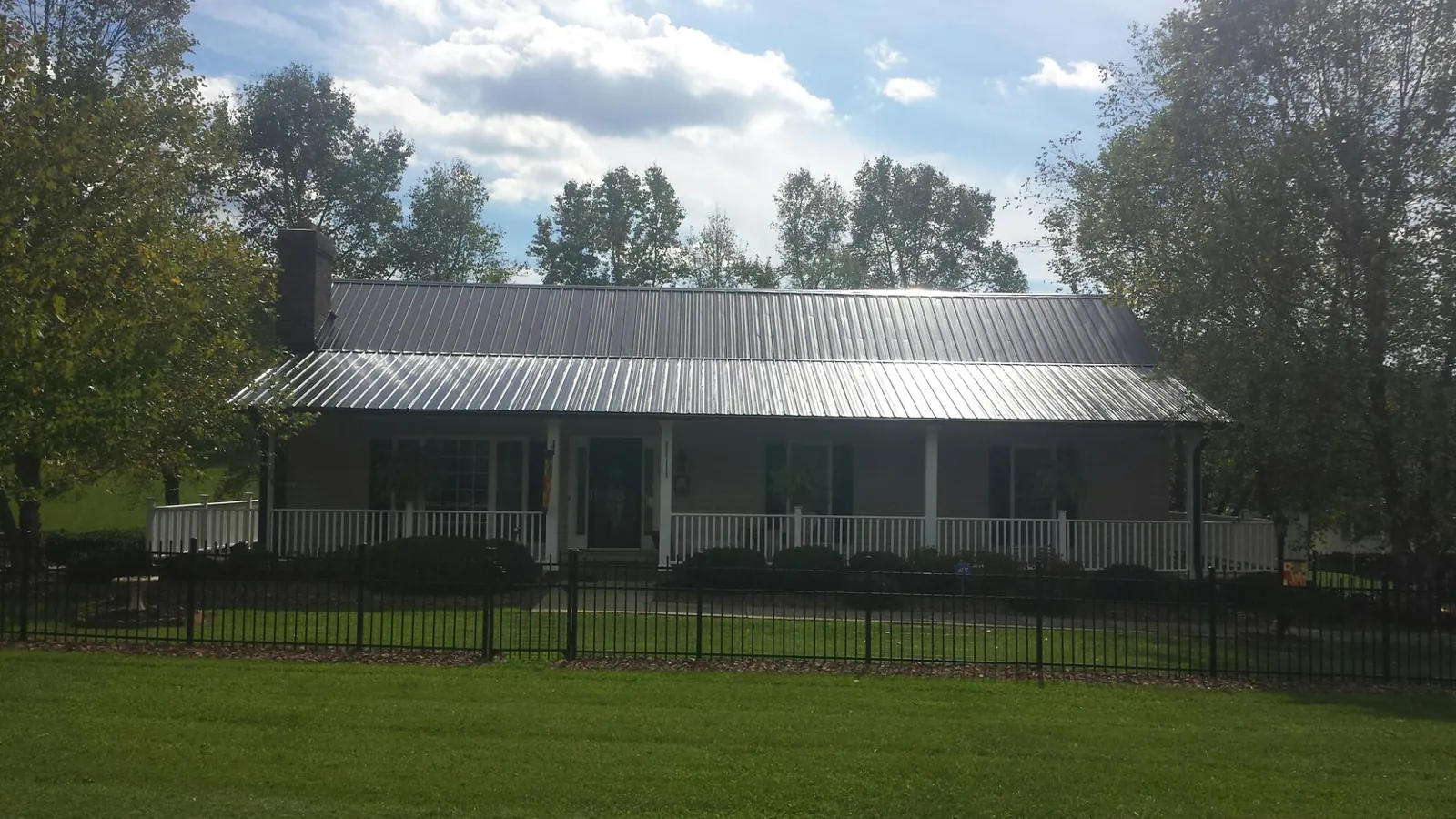 Gray metal roof on a brick ranch with a full width front porch — Gutter Guard Installation work by our crew in La Quinta