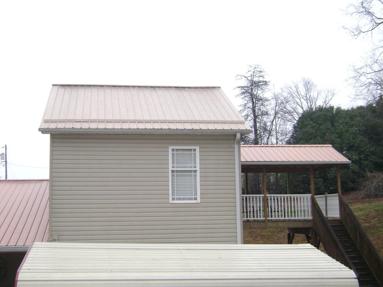 Tan metal roofs on a two story addition and attached porch, from a Roof Replacement job in La Quinta