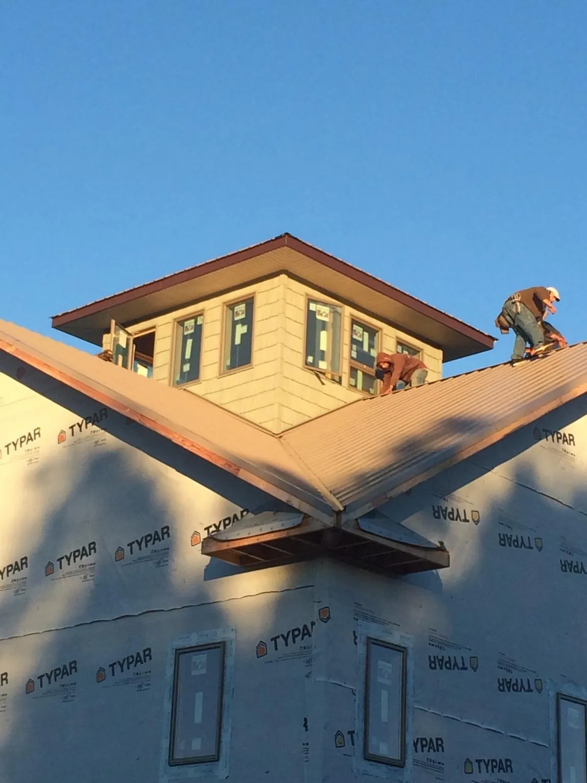 Roofers working around a rooftop cupola on a new metal roof at sunset — Roof Waterproofing in La Quinta by Roofing Brothers